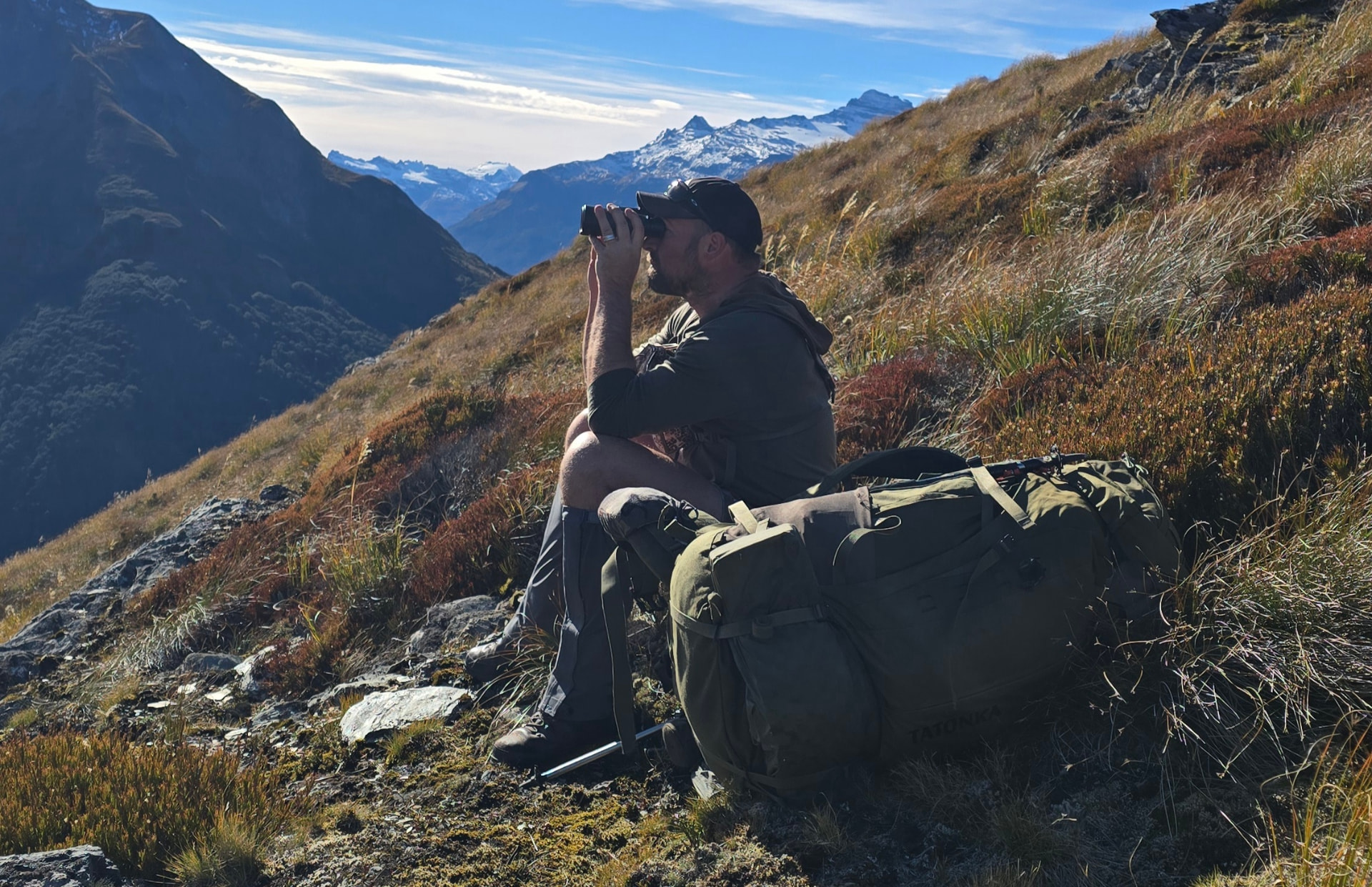 Hunter glassing a tussock face in the New Zealand high country